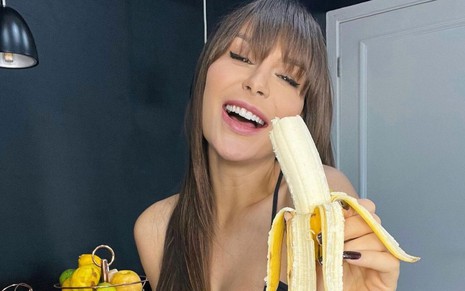 Fernanda Lacerda rindo enquanto segura uma banana descascada