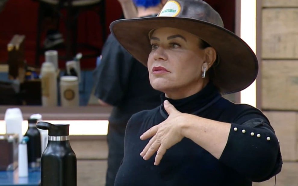 Foto de Flor Fernandez; ela veste blusa preta e usa chapéu de fazendeira na cabeça