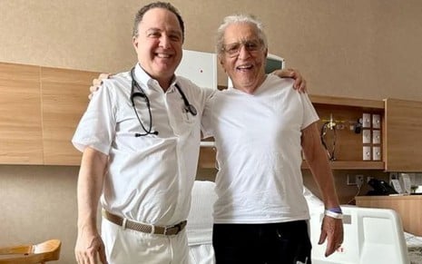 De branco, o médico Roberto Kalil abraça o comediante Carlos Alberto de Nóbrega em um hospital