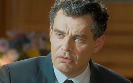 O ator Carmo Dalla Vecchia com expressão séria em cena de Amor Perfeito
