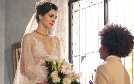 Camila Queiroz caracterizada como Marê; ela está com os cabelos amarrados em um coque e usa um vestido de noiva. O semblante exprime alegria em cena de Amor Perfeito.