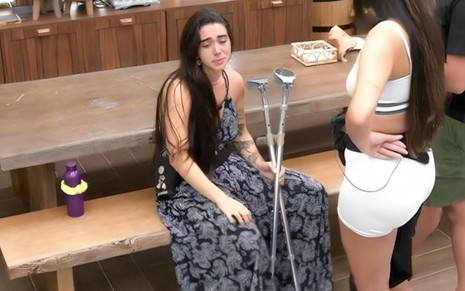 Giovanna Lima sentada, com cara triste, acompanhada de muletas no BBB 24