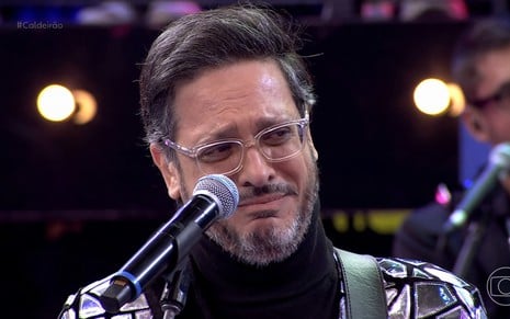 Lucio Mauro Filho contorce o rosto e segura as lágrimas no palco do Caldeirão com Mion