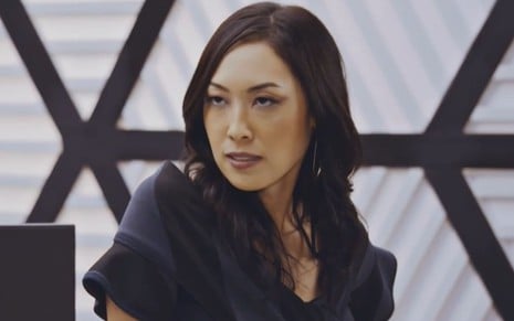 Ana Hikari com expressão séria em cena como Mila na novela Família É Tudo