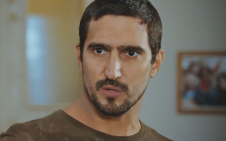 O ator Renato Góes com expressão séria em cena de Família É Tudo