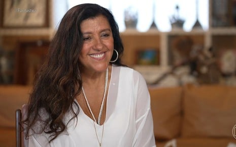 Regina Casé sorri na sala de sua casa em entrevista ao Fantástico