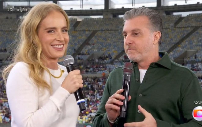 Angélica sorri enquanto é observada por Luciano Huck no Maracanã durante o pré-jogo