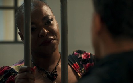 Em cena de Fuzuê, Olivia Araujo está conversando com alguém que está preso em uma cela