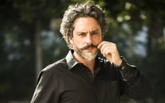 Alexandre Nero caracterizado como José Alfredo, com a mão no bigode, em Império (2014)