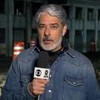 William Bonner com um casaco jeans e um microfone da Globo no Jornal Nacional