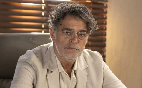 Eduardo Moscovis usa terno e camisa claros caracterizado como Ariosto, seu personagem na novela No Rancho Fundo