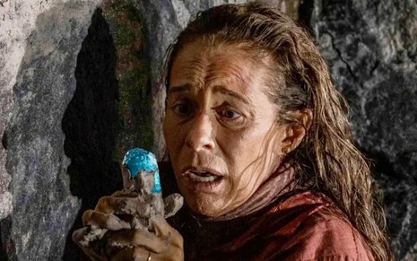 Andrea Beltrão observa com espanto pedra azul em cena da novela No Rancho Fundo, da Globo, como Zefa