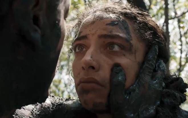 Alice Carvalho caracterizada como Joana; ela encara Irandhir Santos --oTião Galinha--, suja de lama, em cena de Renascer