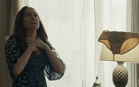 A atriz Camila Morgado como Dona Patroa com expressão de surpresa com uma cueca no abajur em cena de Renascer