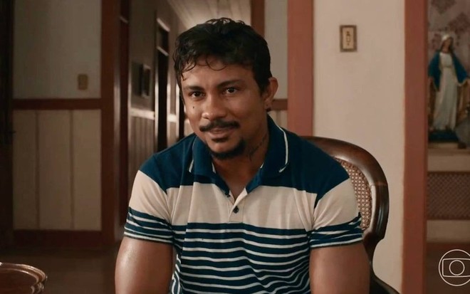 O ator Xamã está sorrindo maliciosamente em cena da novela Renascer, da Globo, como Damião