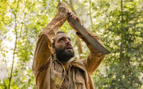 O ator Humberto Carrão está em cena de Renascer segurando um facão diante do corpo e olhando para cima como José Inocêncio