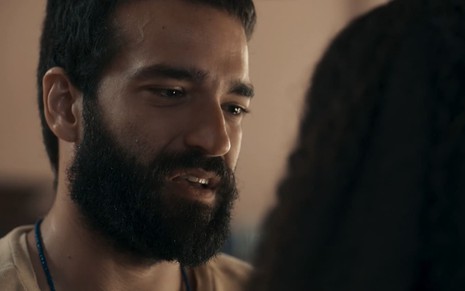 Humberto Carrão caracterizado como José Inocêncio; ele está sério enquanto encara Duda Santos, a Maria Santa, em cena de Renascer