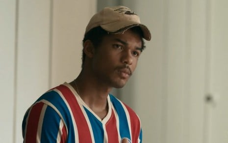 O ator Juan Paiva usa boné e camisa de time de futebol em cena como João Pedro na novela Renascer, da Globo