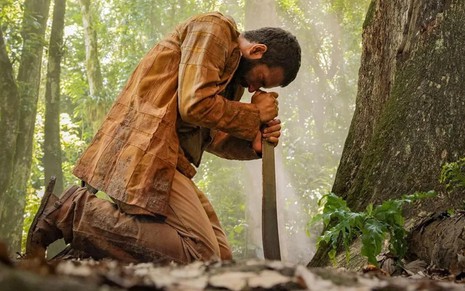 O ator Humberto Carrão finca facão no pé de árvore em cena de Renascer na pele do José Inocêncio