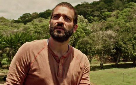 Humberto Carrão está olhando para o céu em cena de Renascer como o personagem José Inocêncio