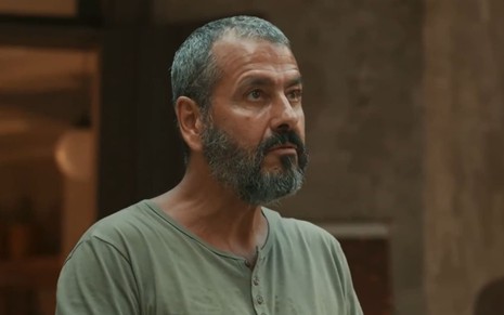Marcos Palmeira caracterizado como José Inocêncio; ele usa uma camiseta verde, está sério e encara um ponto fixo em cena de Renascer