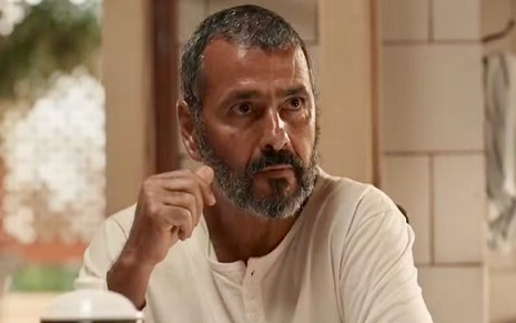 O ator Marcos Palmeira está em cena da novela Renascer com uma camisa branca de manga longa e tem expressão séria