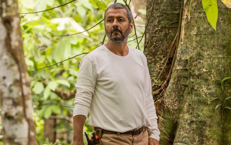 Marcos Palmeira, o José Inocêncio, usa uma blusa branca e está cercado por vegetação em cena de Renascer