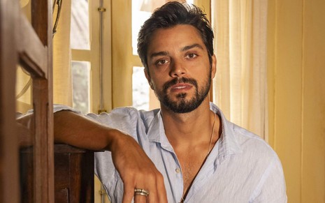 Rodrigo Simas usa camisa clara e posa em cenário do remake de Renascer como o personagem José Venâncio