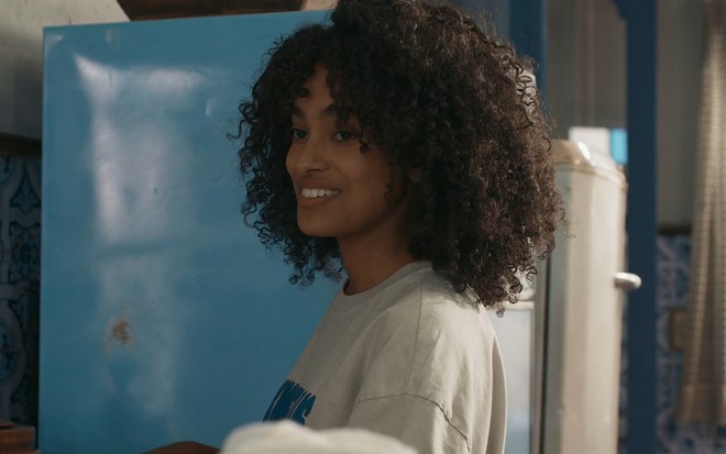 A atriz Lívia Silva está sorrindo em cena da novela Renascer, da Globo, como Teca