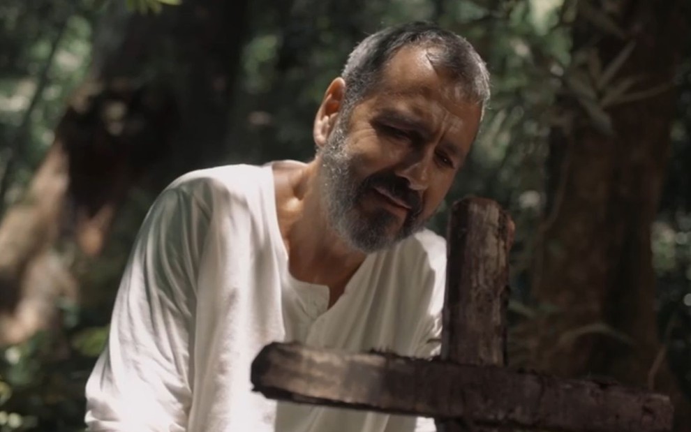Com expressão triste, Marcos Palmeira como José Inocêncio chora diante de um túmulo em cena de Renascer