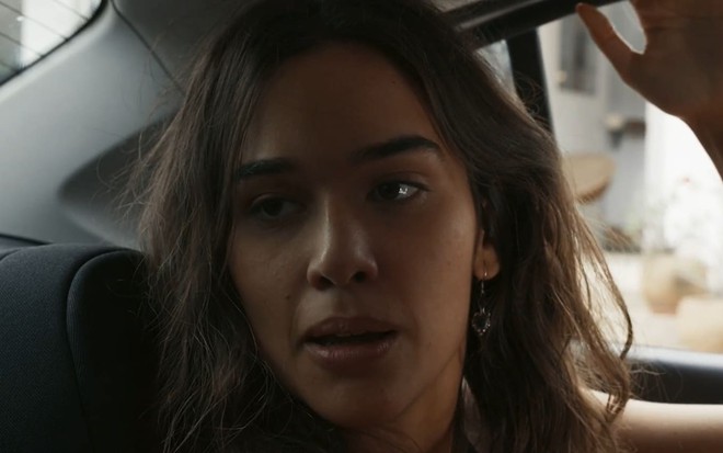 Theresa Fonseca caracterizada como Mariana; ela está num carro e tem o semblante espantado em cena de Renascer