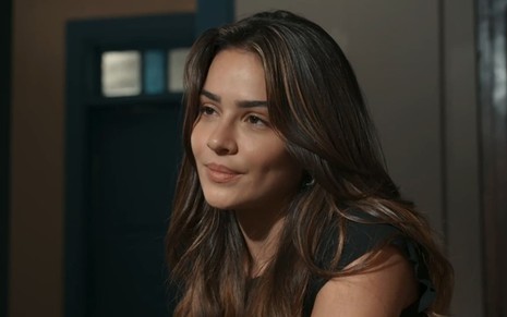 Giullia Buscacio caracterizada como Sandra; ela está séria em cena de Renascer