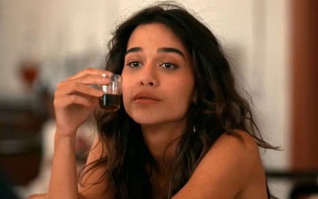 A atriz Theresa Fonseca como Mariana segurando uma dose de cachaça em cena de Renascer