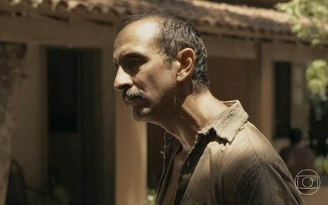 Irandhir Santos está de perfil, sério, em cena da novela Renascer, da Globo, como Tião Galinha