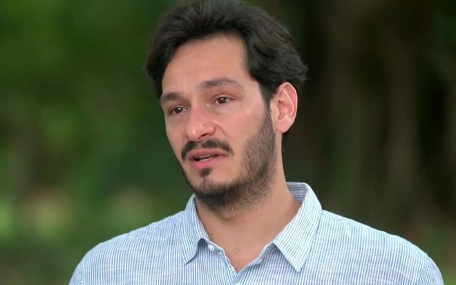 Bruno Luperi usa uma camisa social azul clara e está sério durante entrevista ao Globo Repórter