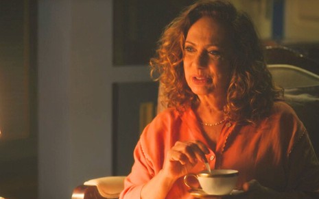 A atriz Eliane Giardini como Agatha segurando uma xícara de chá em referência à cena de Corra em Terra e Paixão