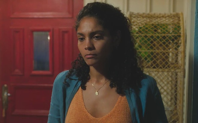 Barbara Reis caracterizada como Aline; ela usa uma camiseta verde e tem o semblante abalado em cena de Terra e Paixão