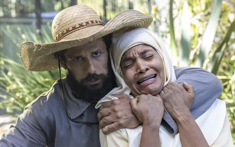Amaury Lorenzo usa chapéu e arrasta Barbara Reis à força em cena da novela Terra e Paixão; ele está caracterizado como Ramiro