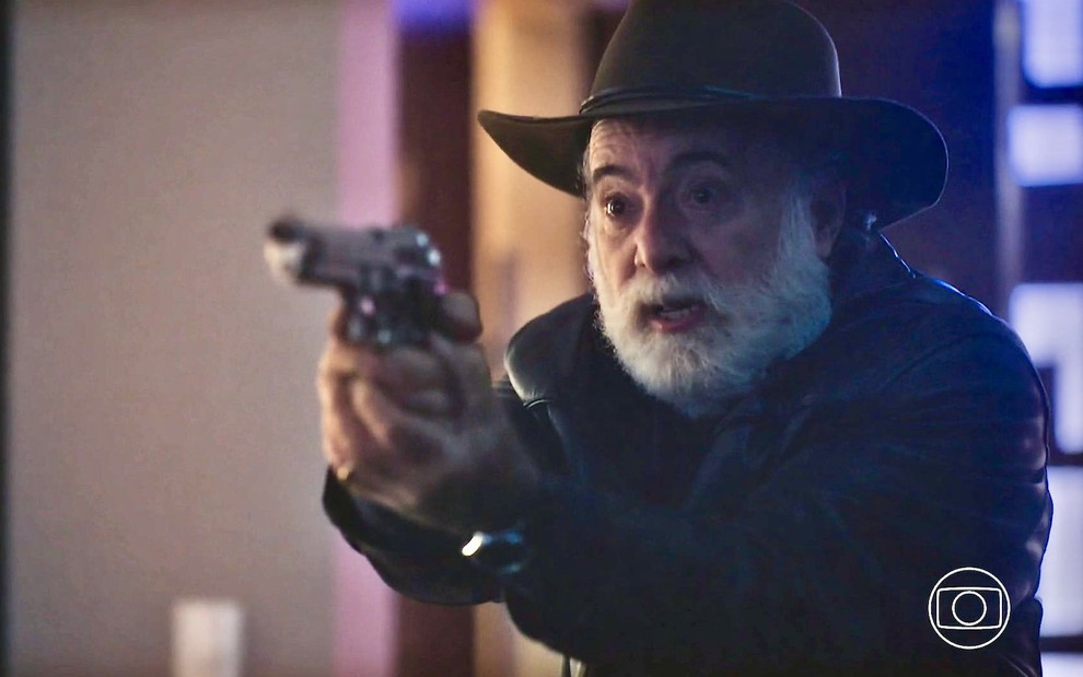 O ator Tony Ramos está apontando uma arma em cena da novela Terra e Paixão como o vilão Antônio
