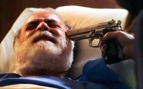 Tony Ramos está deitado e tem arma encostada na sua cabeça em cena da novela das nove da Globo, Terra e Paixão