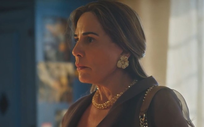 Gloria Pires caracterizada como Irene; ela está de perfil, usa joias douradas e parece espantada em cena de Terra e Paixão