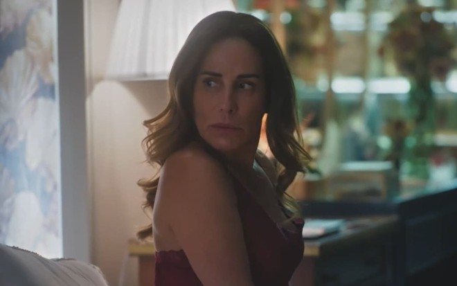 Gloria Pires caracterizada como Irene; ela usa uma camisola vermelha e parece séria em cena de Terra e Paixão
