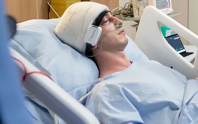 O ator Johnny Massaro está com faixa na cabeça em leito de hospital como Daniel em cena da novela Terra e Paixão