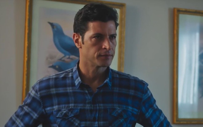 Leandro Lima caracterizado como Marino; ator usa uma camisa azul e parece tenso em cena de Terra e Paixão