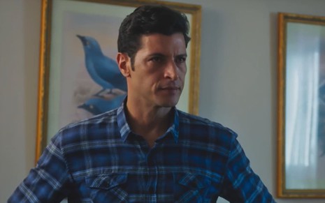 Leandro Lima caracterizado como Marino; ator usa uma camisa azul e parece tenso em cena de Terra e Paixão