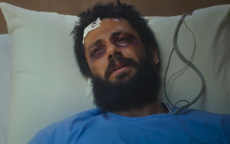 Amaury Lorenzo caracterizado como Ramiro; ele usa uma camisola hospitalar azul e tem os olhos roxos em cena de Terra e Paixão. O semblante exprime agonia.