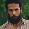 Amaury Lorenzo caracterizado como Ramiro; ele usa uma camisa bege e parece tenso e confuso em cena de Terra e Paixão