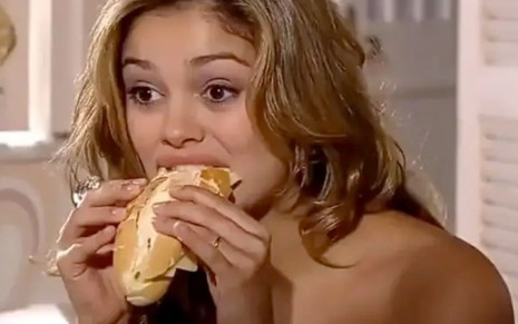 Sophie Charlotte como Stéphany dá uma mordida em um pão francês em cena de Ti Ti Ti