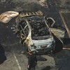 Foto de dois carros queimados em uma avenida