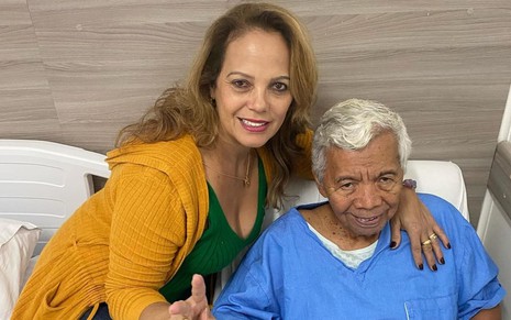 Janilda Nogueira está abraçada a Gonçalo Roque, que encara a câmera, sério; ela sorri para a foto, e ele está com uma camisola de hospital
